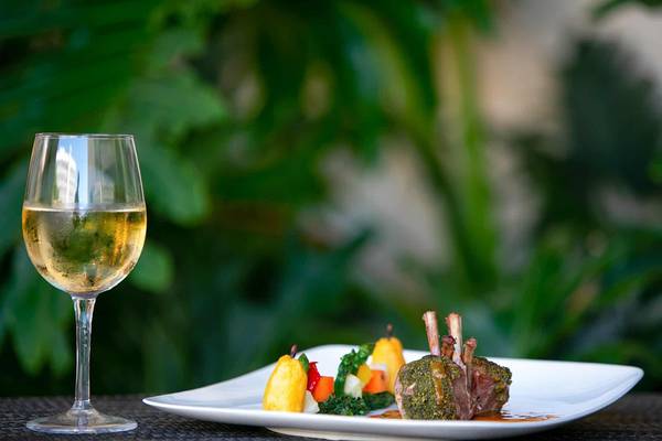 Ein Glas mit weißem Wein neben einem Gericht im Golden Bay Beach Hotel.
