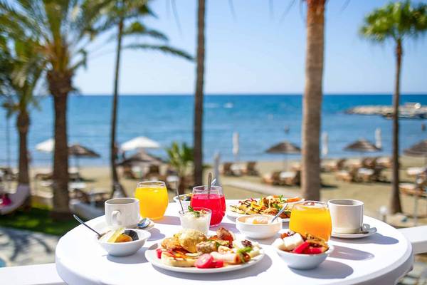 Frühstück auf der Terrasse am Strand mit Blick auf das Meer und Palmen.