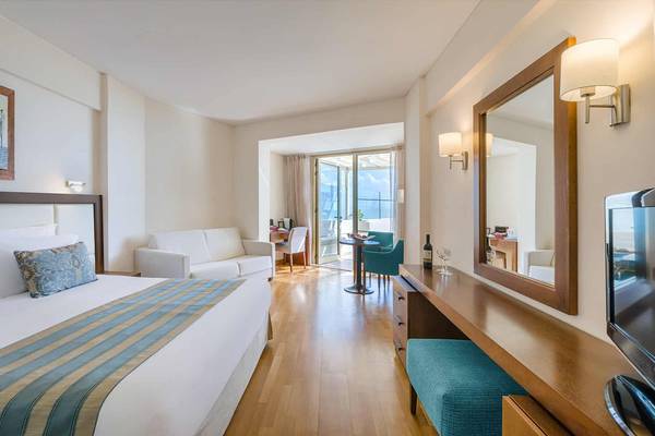 Hotelzimmer im Golden Bay Beach Hotel mit großem Bett, Couch und Tisch.