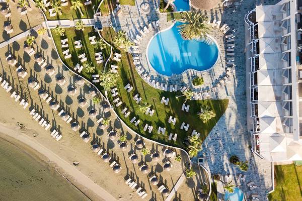 Luftaufnahme des Golden Bay Beach Hotel mit Pool, Liegestühlen und Gebäuden am Strand