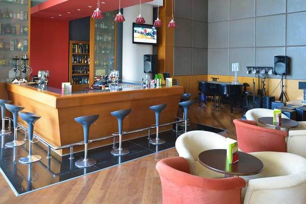 Die Bar im Golden Bay Beach Hotel mit einer Theke, Stühlen und einem Fernseher.