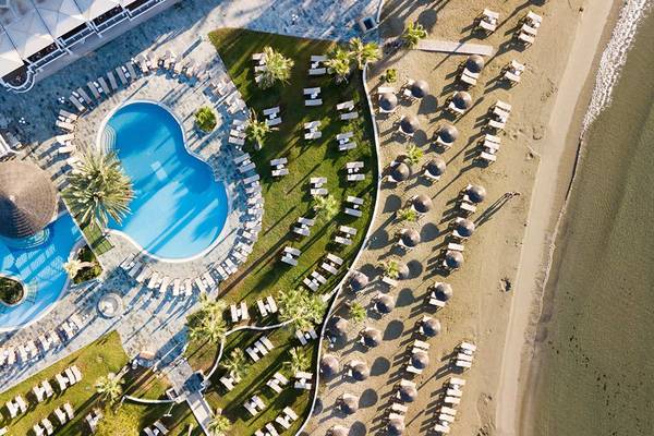 Luftaufnahme des Golden Bay Beach Hotel mit großem Pool und vielen Sonnenliegen am Strand