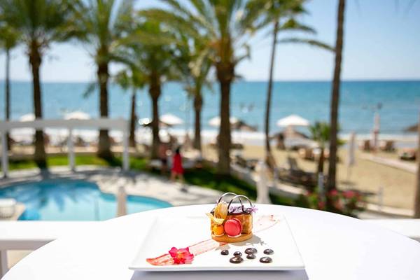 Aussicht auf den Strand vom Golden Bay Beach Hotel mit einem Dessert auf dem Tisch.