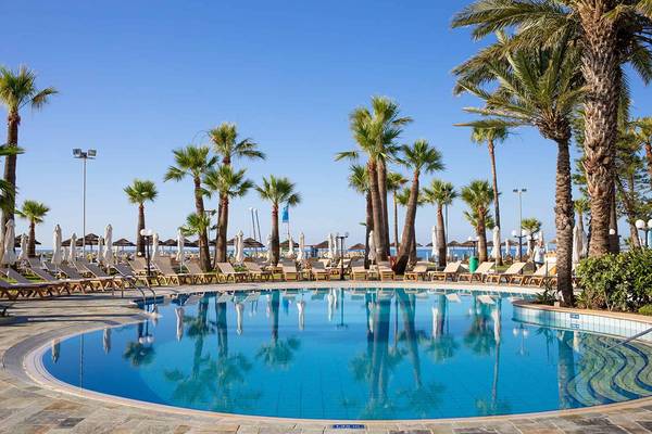 Der Pool im Golden Bay Beach Hotel mit Palmen und Sonnenliegen am Rand.