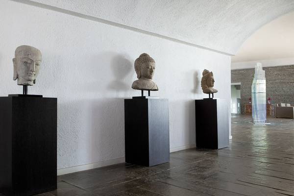 Drei Buddha-Kopf-Skulpturen auf schwarzen Sockeln im Minos Palace Hotel & Suites.
