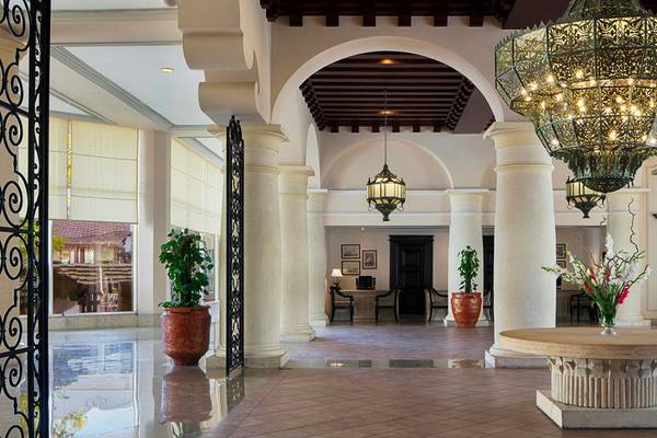 Eingangsbereich des Sheraton Sharm Hotel mit großen Säulen, hängenden Kronleuchtern und einer Tischvase.