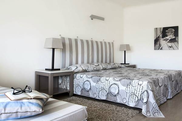 Schlafzimmer im Minos Palace Hotel & Suites mit zwei Betten, Nachttischen und Lampen.