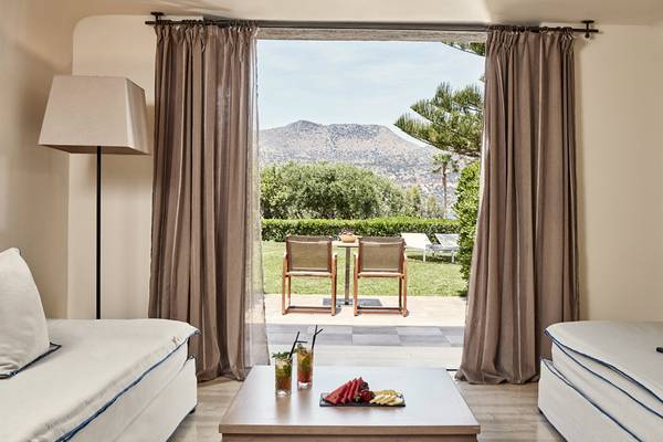 Innenraum der Minos Palace Hotel & Suites mit Blick auf eine Terrasse und Garten