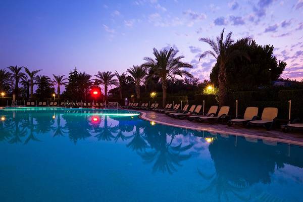 Außenpool des Side Sun Hotels bei Nacht mit blauem Wasser und reflektierten Palmen