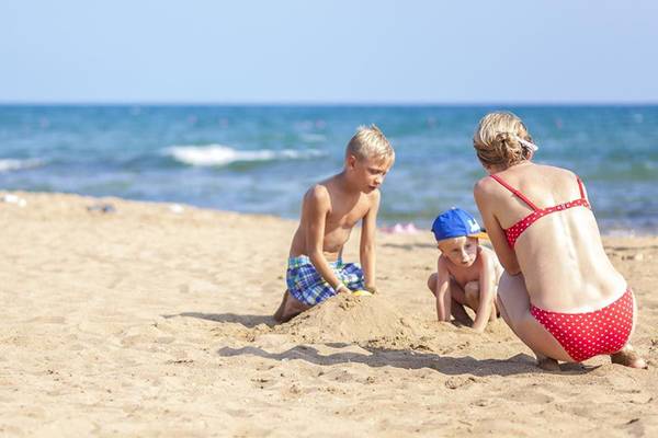 Mutter und Kinder am Strand vor dem Side Sun Hotel, spielend im Sand.
