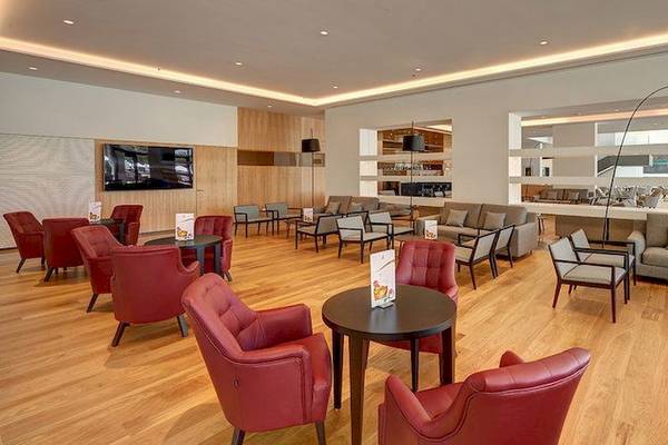 Lobby des Hipotels Playa de Palma Palace mit roten Stühlen, Tischen und Sofas.