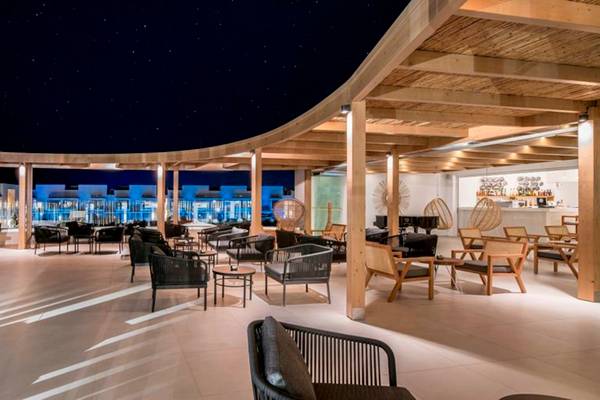 Nachtansicht der Terrasse des Insula Alba Resort & Spa mit vielen Sitzgelegenheiten und Holzkonstruktionen.