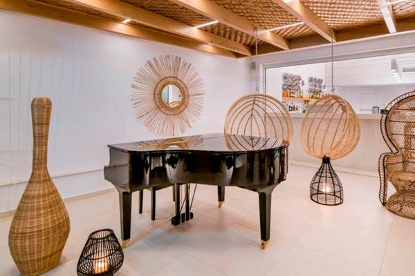 Loungebereich im Insula Alba Resort & Spa mit einem Klavier, Rattanmöbeln und einer Wanddekoration.