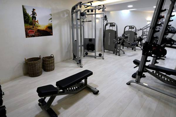 Fitnessstudio im Insula Alba Resort & Spa mit verschiedenen Geräten und einer Wand mit einer Laufposter.