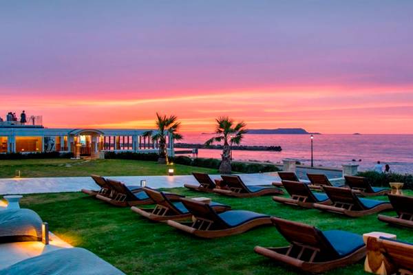 Abendstimmung im Insula Alba Resort & Spa mit Sonnenuntergang am Meer und Loungebereich auf der Wiese.
