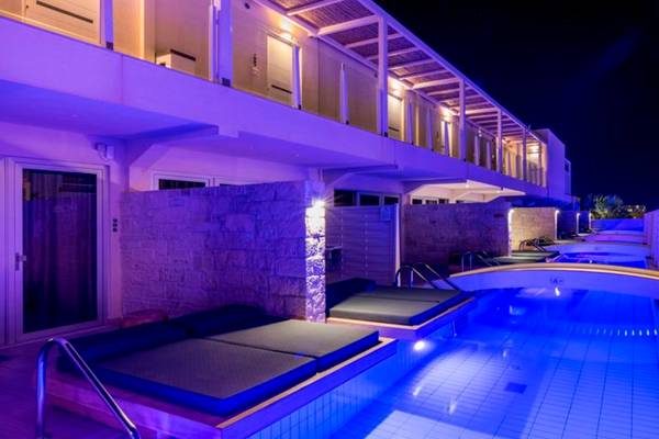 Poolbereich des Insula Alba Resorts & Spa bei Nacht mit blauer Beleuchtung und Liegen.