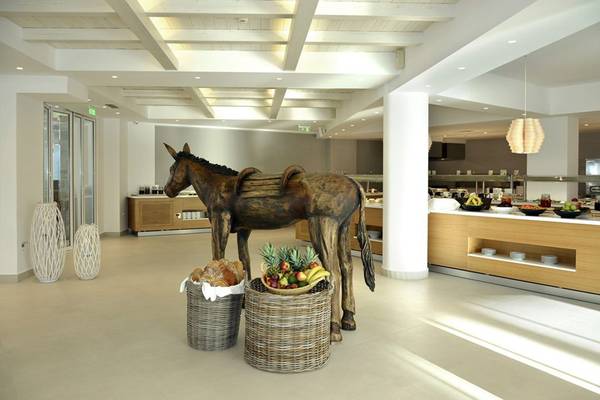 Ein Speisesaal im Insula Alba Resort & Spa mit einer großen Pferdestatue und Körben voller Früchte und Brot.