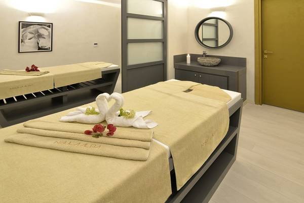 Massageraum im Insula Alba Resort & Spa mit zwei Massagebetten, einem Waschbecken und einem Spiegel.