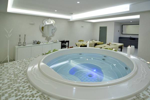 Whirlpool im Insula Alba Resort & Spa mit weißen Fliesenboden und dekorativen Kerzen.
