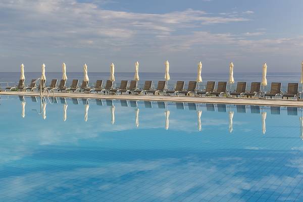 Ein Swimmingpool mit Sonnenschirmen und Sonnenliegen neben dem Meer, zugeschnitten auf das Hotel Domes of Corfu, Autograph Collection.
