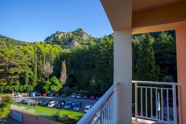 Blick von einem Hotelbalkon auf einen Parkplatz und einen Berg