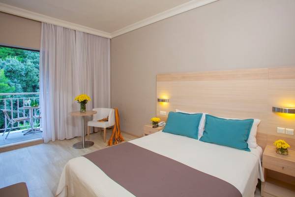 Hotelzimmer im Domes of Corfu, Autograph Collection mit Balkon, Tisch, Stühlen und Blumen.