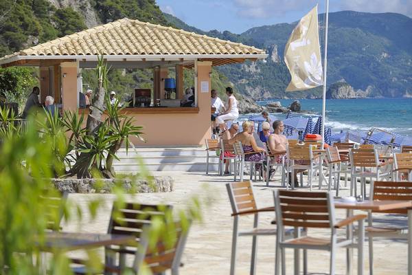 Gäste sitzen an Tischen auf der Terrasse der Strandbar des Domes of Corfu, Autograph Collection.