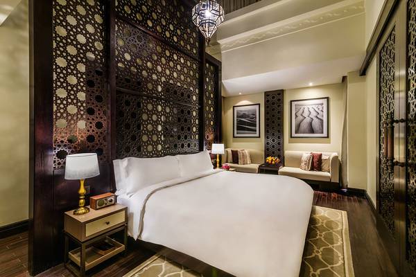 Das Innendesign eines Schlafzimmers im Ritz-Carlton Ras Al Khaimah, Al Wadi Desert mit einem großen Bett, dekorativen Wandpaneelen und Möbeln.