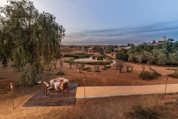 Abendessen im Freien im Ritz-Carlton Ras Al Khaimah, Al Wadi Desert, mit Tisch und Fackeln.