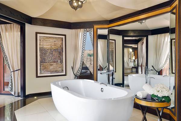 Badezimmer im The Ritz-Carlton Ras Al Khaimah, Al Wadi Desert mit Badewanne, Spiegeln und Dekor.