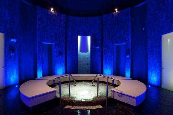 Jacuzzi im Ritz-Carlton Ras Al Khaimah, Al Wadi Desert, mit blauer Beleuchtung und runden Bänken.