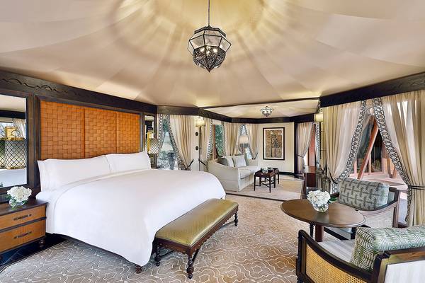 Schlafzimmer im The Ritz-Carlton Ras Al Khaimah, Al Wadi Desert mit einem großen Bett, Nachttischen und einem Sitzbereich.