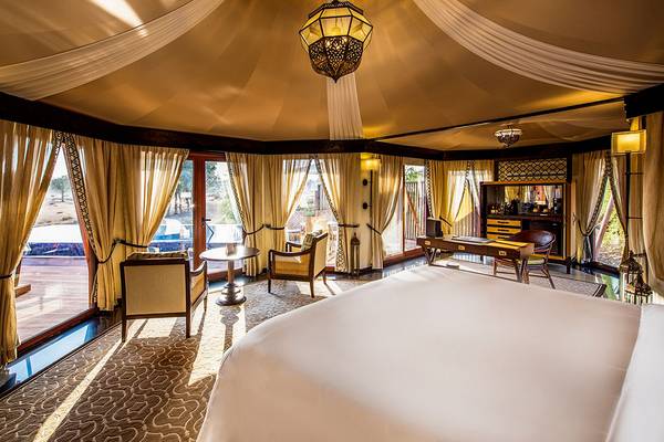 Das Schlafzimmer im Ritz-Carlton Ras Al Khaimah, Al Wadi Desert zeigt ein großes Bett und ein Arbeitszimmer.