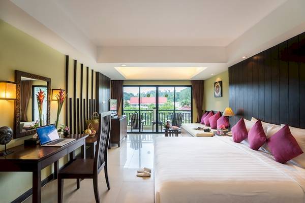Innenansicht der Suite im Khao Lak Emerald Beach Resort mit Bett, Schreibtisch, Laptop und Balkon.