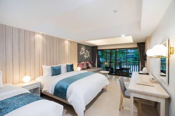 Suite-Zimmer im Khao Lak Emerald Beach Resort mit drei Betten und Blick auf den Garten.