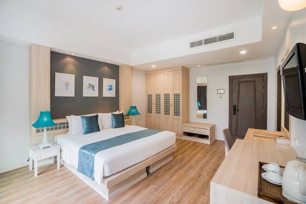 Innenansicht eines Hotelzimmers im Khao Lak Emerald Beach Resort & Spa mit Doppelbett, Nachttischen, Lampen und Fernseher.