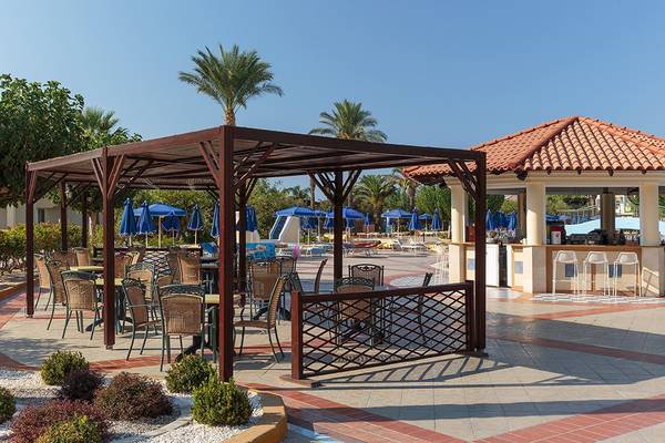 Terrasse des Lindos Princess Beach Hotels mit Tischen, Stühlen und Sonnenschirmen neben einem Barbereich.