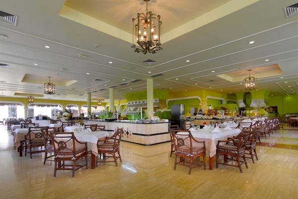 Innenansicht des Restaurants im Grand Palladium White Sand Resort & Spa mit gedeckten Tischen und Kronleuchtern.