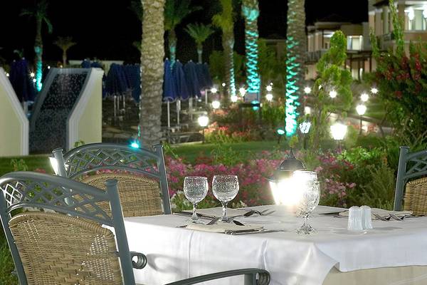 Außenbereich des Lindos Princess Beach Hotels mit beleuchtetem Tisch und Stühle.