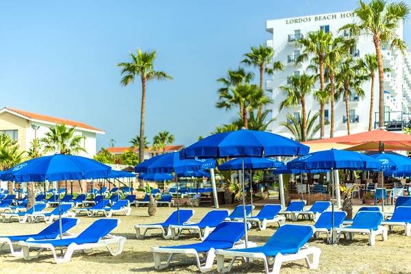 Strand des Lordos Beach Hotels mit vielen Liegestühlen und blauen Sonnenschirmen