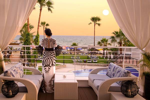 Frau auf dem Balkon des Lordos Beach Hotel mit Blick auf das Meer und Sonnenuntergang.