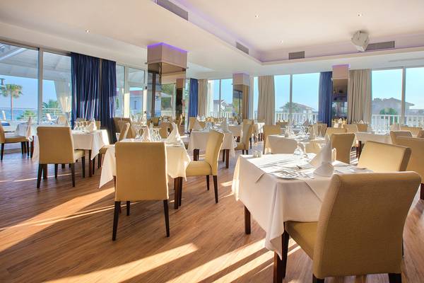 Innenansicht des Restaurants im Lordos Beach Hotel mit mehreren gedeckten Tischen und Stühlen.