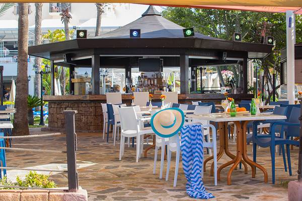 Terrasse des Lordos Beach Hotels mit Tischen, Stühlen und einem Pavillon.