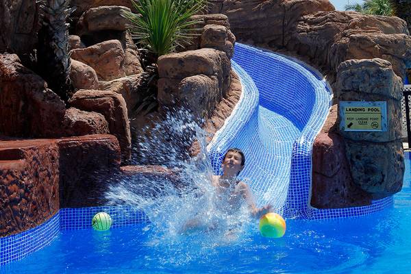 Ein Kind spielt im Pool des Lordos Beach Hotels und kommt von der Rutsche.