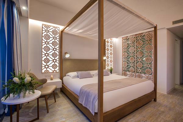 Schlafzimmer im Lordos Beach Hotel mit vierpfostenbett, blauem Vorhang und Blumen auf dem Tisch