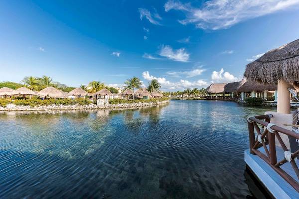Außenansicht des Grand Palladium White Sand Resort & Spa mit Blick auf einen Wasserweg und Strohhütten.