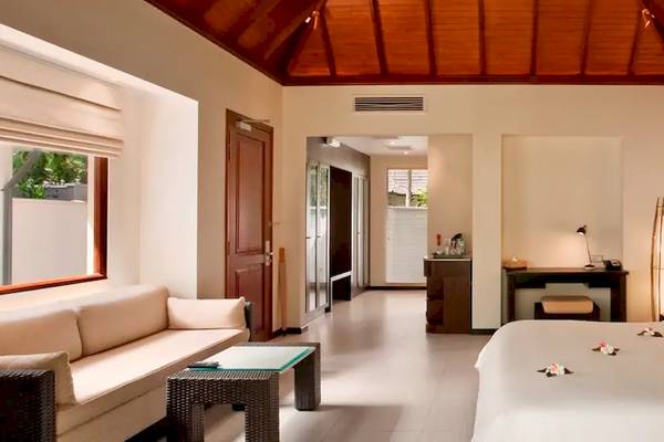Innenansicht eines Coco de Mer & The Black Parrot Suite Zimmers mit Bett, Couch, Schreibtisch und Lampe.