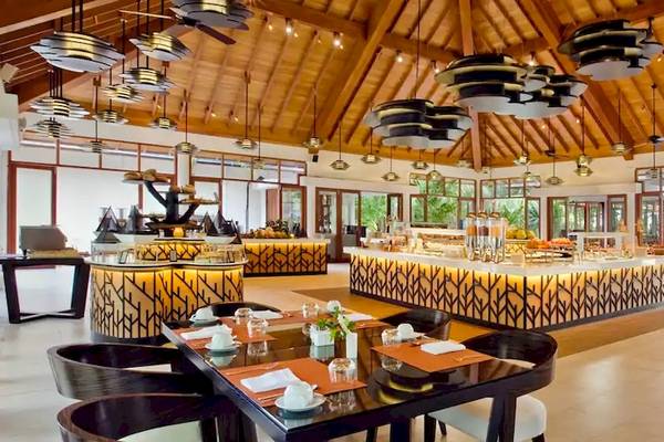 Innenansicht des Restaurants im Coco de Mer & The Black Parrot Suites Hotel mit Esstischen, Stühlen und einer großen Theke.