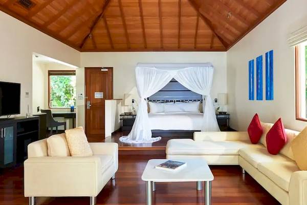 Wohnzimmer der Coco de Mer & The Black Parrot Suites mit Sofa, Couch, Tisch, Fernseher und Bett