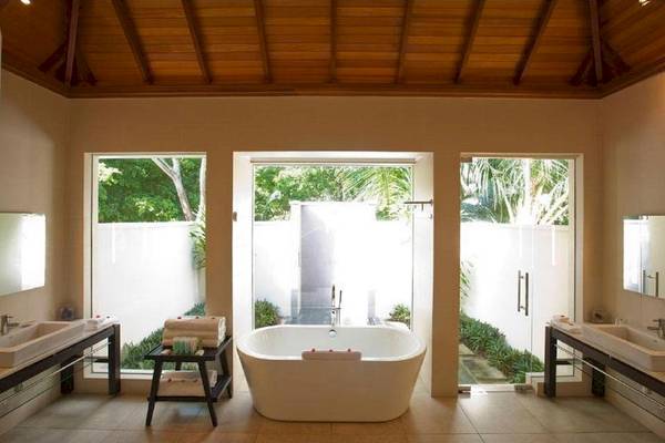 Badezimmer im Coco de Mer Hotel mit Badewanne, Waschbecken und Glastüren